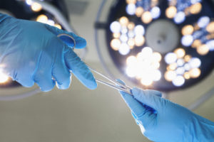 surgeon with blue gloves holding surgical instruments