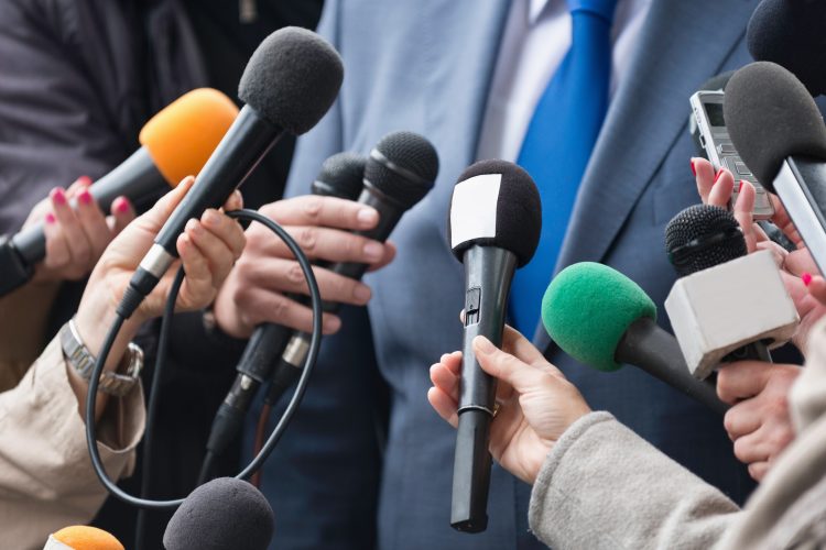 Man in a suit in front of microphones