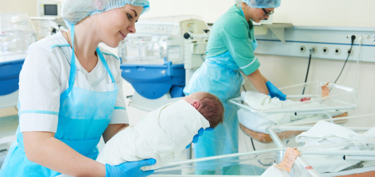 newborn baby being held by a nurse in hospital