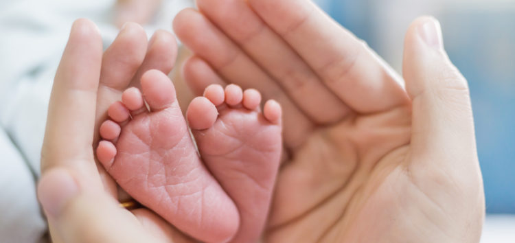 Mother’s hands holding newborn baby feet